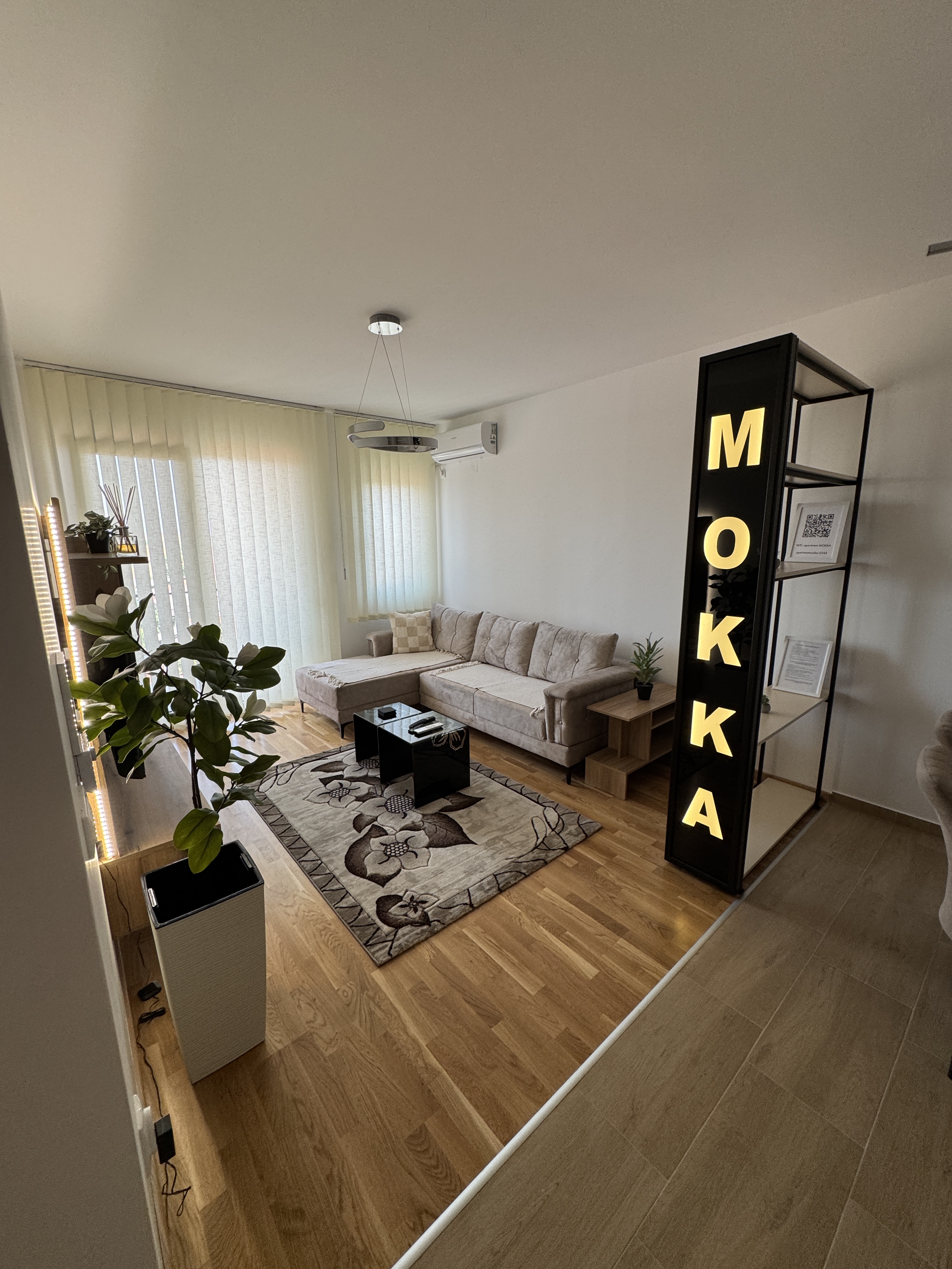 Dnevni boravak apartmana MOKKA sa bež garniturom i osvetljenim natpisom